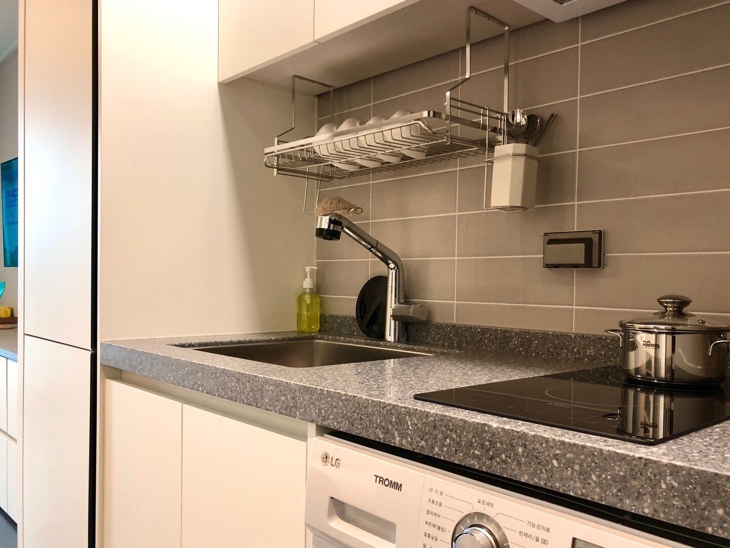 Una cucina con un lavello doppio, uno scolapiatti, un bollitore e un piano cottura.