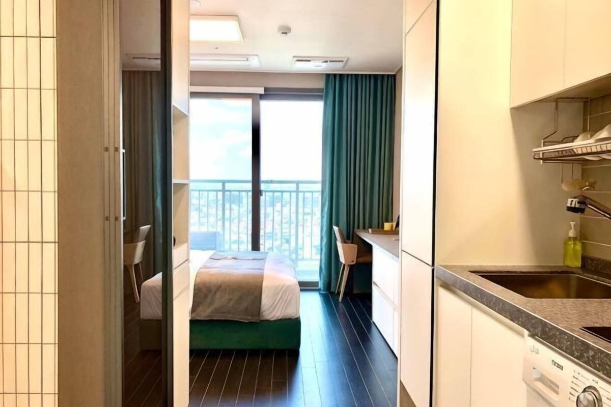 Habitación de hotel con cama, escritorio, silla, balcón y kitchenette.
