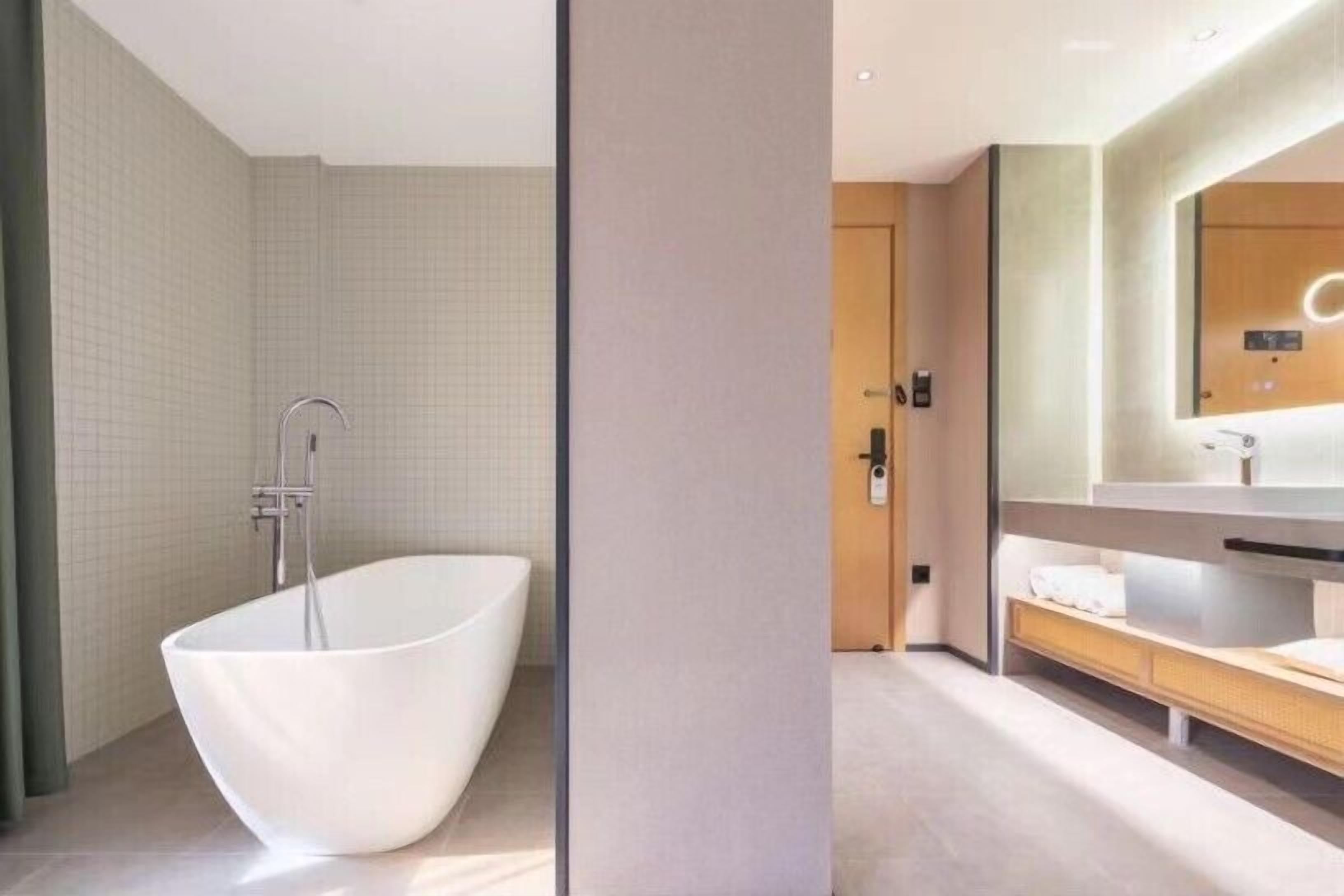 A modern bathroom with a freestanding bathtub, a large mirror, and a wooden vanity.