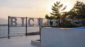 A metal gate with the letters 'BICHAE' and a tiled walkway leading to a body of water. - Sacheon Bichae Pension (Sacheon)
