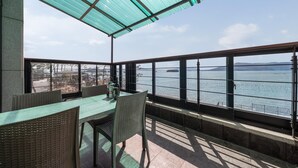 A terrace with a table and chairs, overlooking a body of water with a view of distant land and a clear sky. - Sacheon Bichae Pension (Sacheon)
