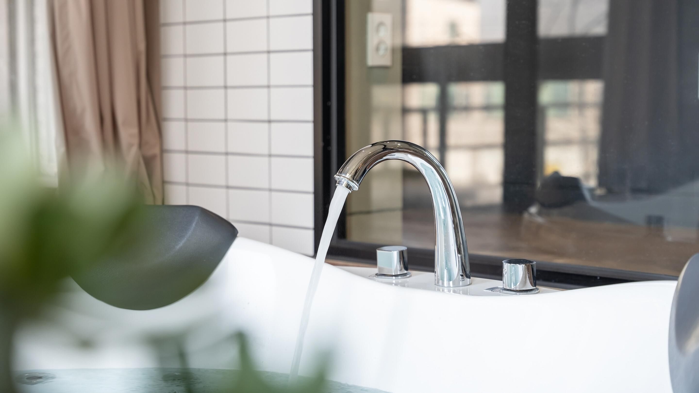 A modern bathroom with a chrome faucet, a white sink, and a glass shower enclosure.