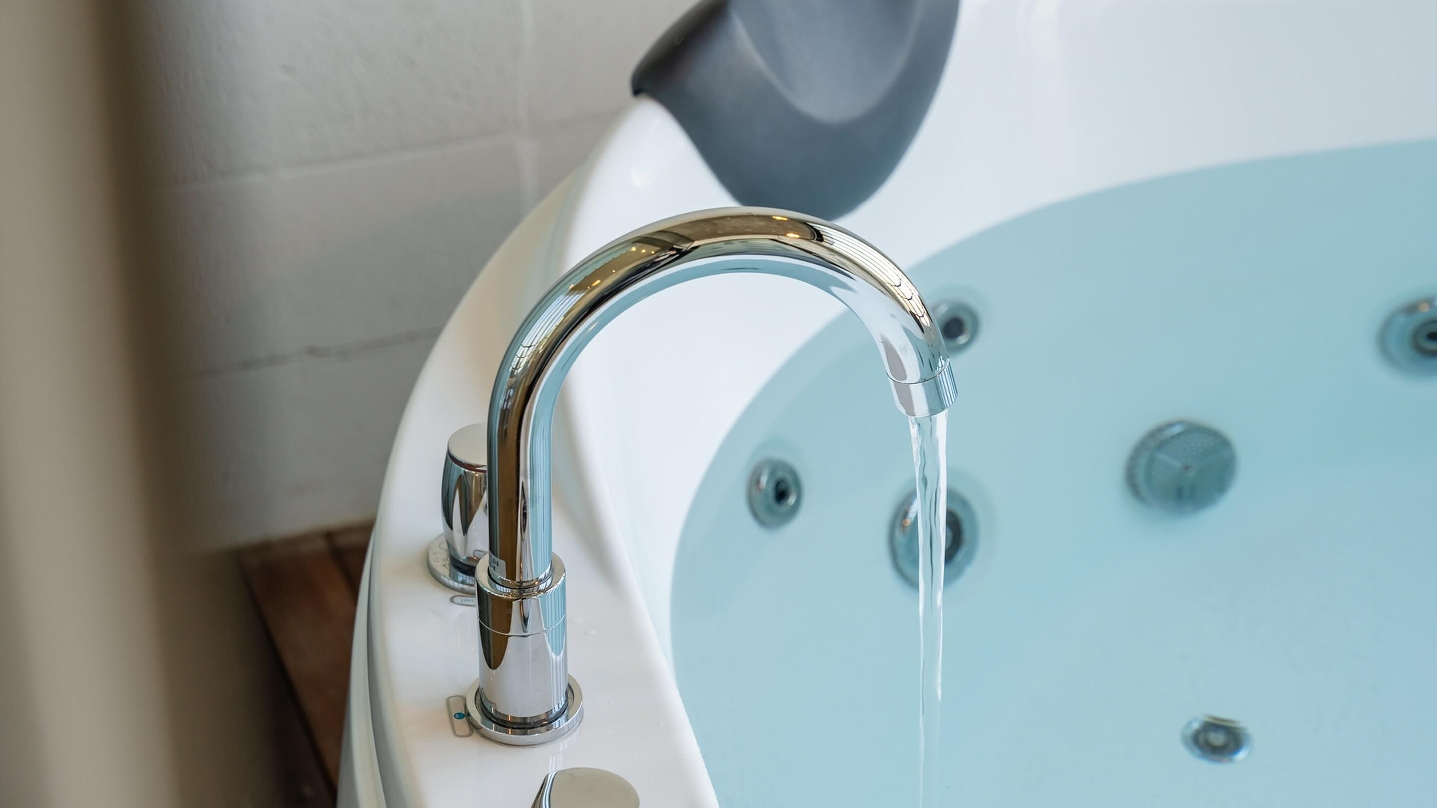 A bathroom with a white bathtub and a chrome faucet.