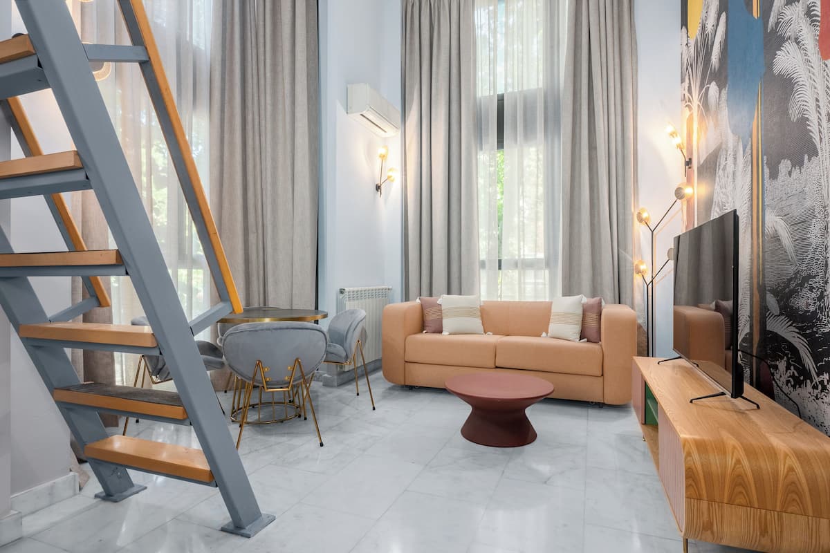 A modern living room with a staircase, a sofa, a coffee table, and a TV stand.