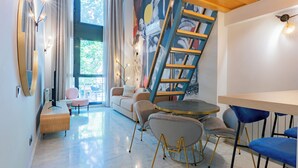 A modern living room with a sofa, chairs, a round table, and a staircase. - Smartr Madrid Las Ventas  (Madrid)