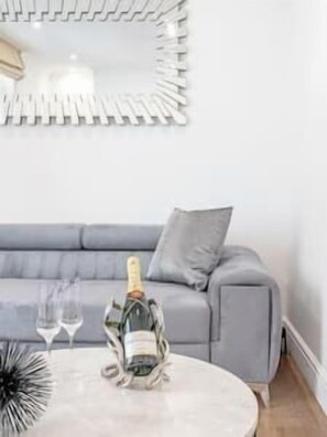 Una sala de estar moderna con un sofá gris, una mesa redonda de centro y un espejo decorativo.