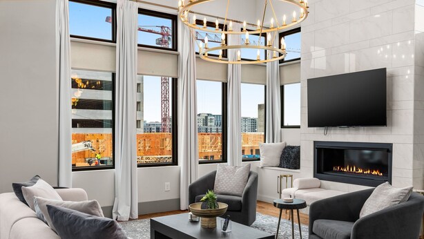 A modern living room with a fireplace, large windows, and a flat-screen TV. - Luxe Getaway with Hot Tub (Nashville)