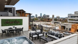 A rooftop terrace with a hot tub, seating area, and a city view. - Luxe Getaway with Hot Tub (Nashville)