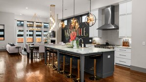 A modern kitchen with a large island, bar stools, and pendant lighting. - Luxe Getaway with Hot Tub (Nashville)