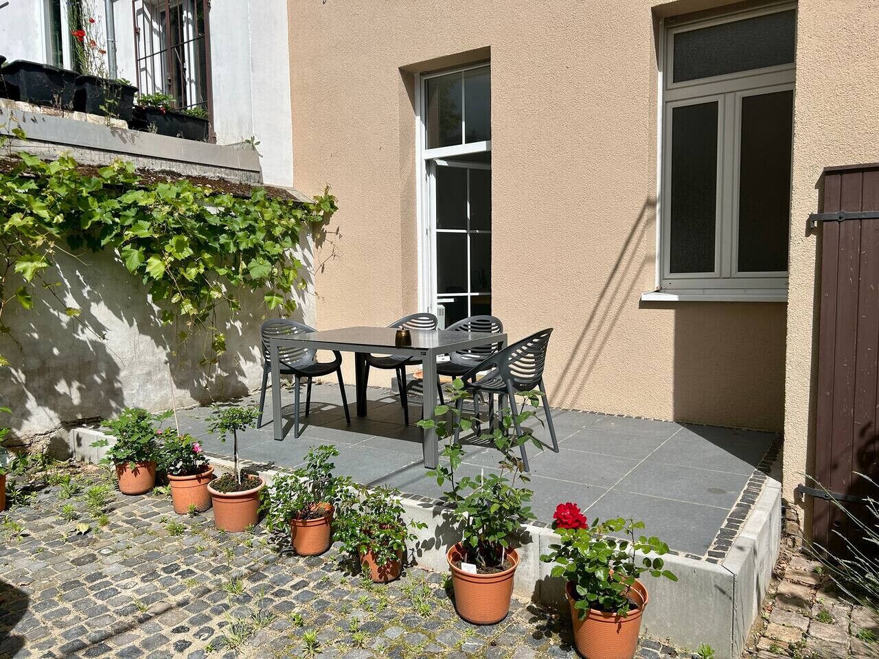 A patio with a table and chairs, surrounded by potted plants.