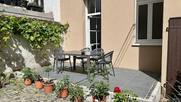 A patio with a table and chairs, surrounded by potted plants.