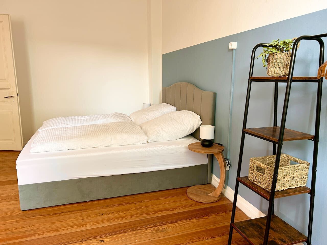 Un dormitorio con cama, mesita de noche, lámpara y repisas con cestas.