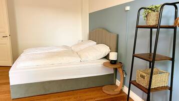 Un dormitorio con cama, mesita de noche, lámpara y repisas con cestas.