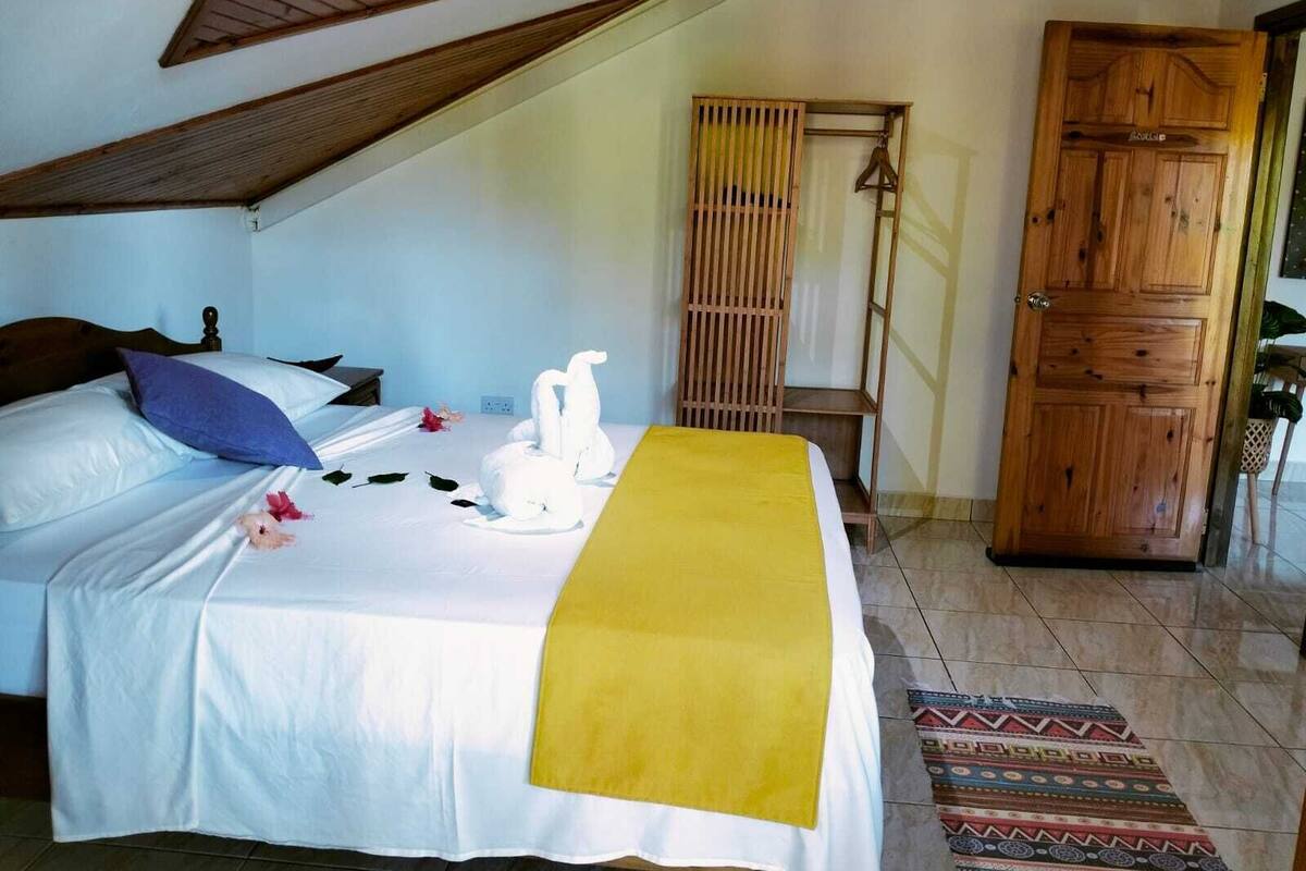 A bedroom with a bed, a wooden wardrobe, and a bamboo screen.