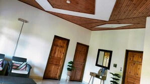 A room with a sloped ceiling, wooden doors, a small table with a mirror, and a potted plant. - La Source Self Catering (La Digue)