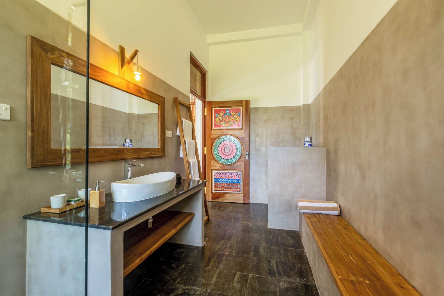 Un baño moderno con un espejo grande, un lavamanos y un banco.