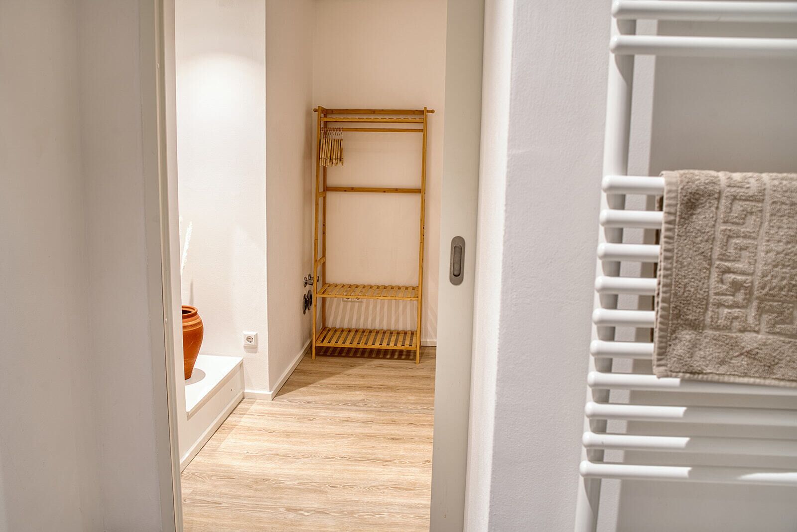 Un pasillo con un banco de madera, un radiador blanco y una toalla sobre él.