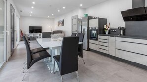 A modern kitchen with a dining area, a built-in oven, and a large window.