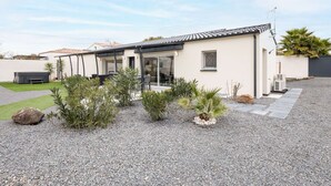 A modern house with a patio, a covered outdoor seating area, and a gravel driveway.