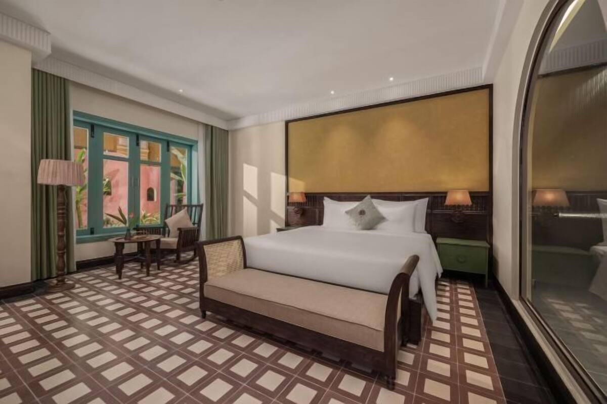 Ein Hotelzimmer mit Bett, einer Couch, einem kleinen Tisch und einem Fenster mit Vorhängen.