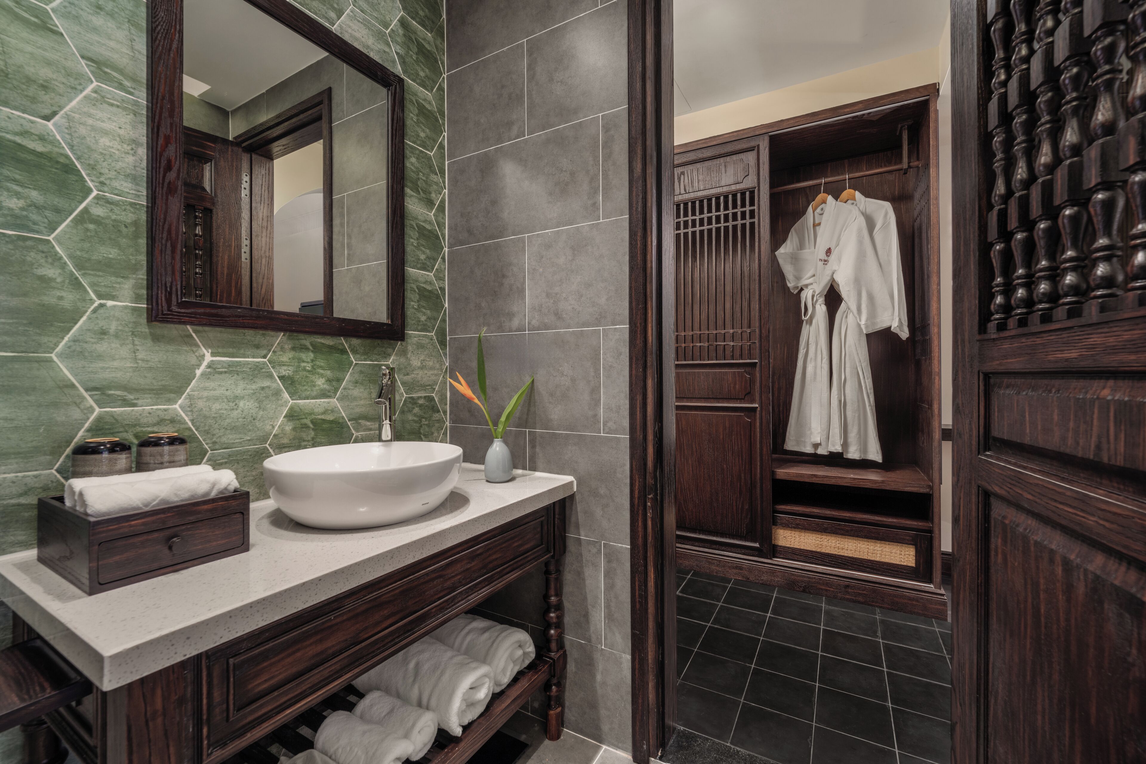 A modern bathroom with a large mirror, a white sink, and dark wood cabinetry.
