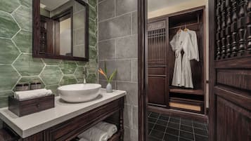 Une salle de bain moderne avec un grand miroir, un lavabo blanc et des meubles en bois foncé.
