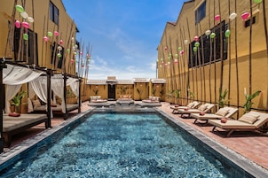 A pool area with lounge chairs and a small seating area with cushions.