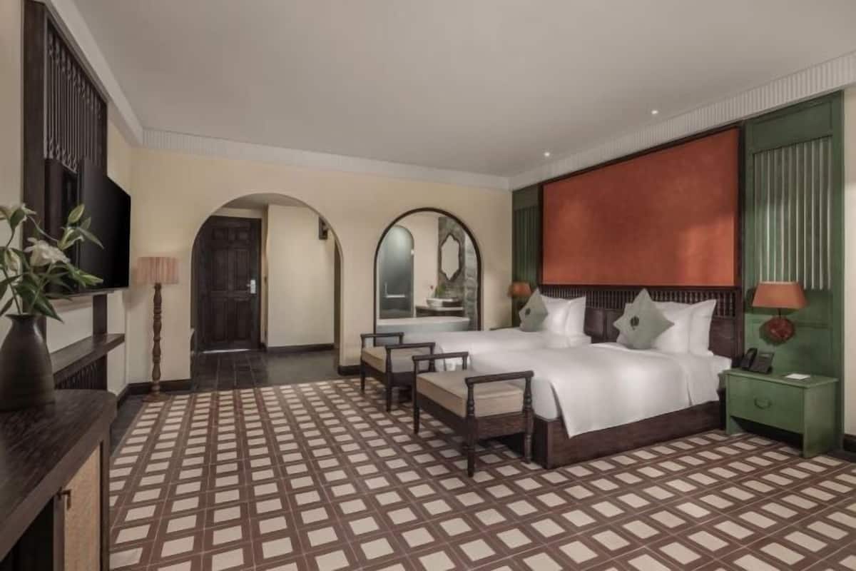 Ein Hotelzimmer mit einem großen Bett, zwei Stühlen, einem Schreibtisch, einem Spiegel und einem Fernseher.