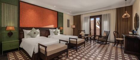 A hotel room with two beds, a sitting area, and a view of the outside through a window.