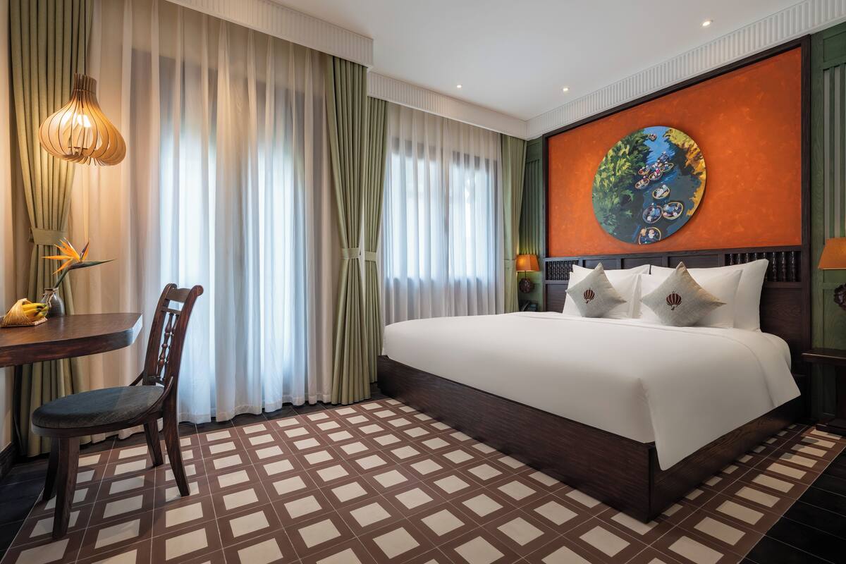 Ein Hotelzimmer mit einem großen Bett, einem Esstisch und einem Stuhl.