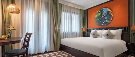A hotel room with a large bed, a dining table, and a chair.