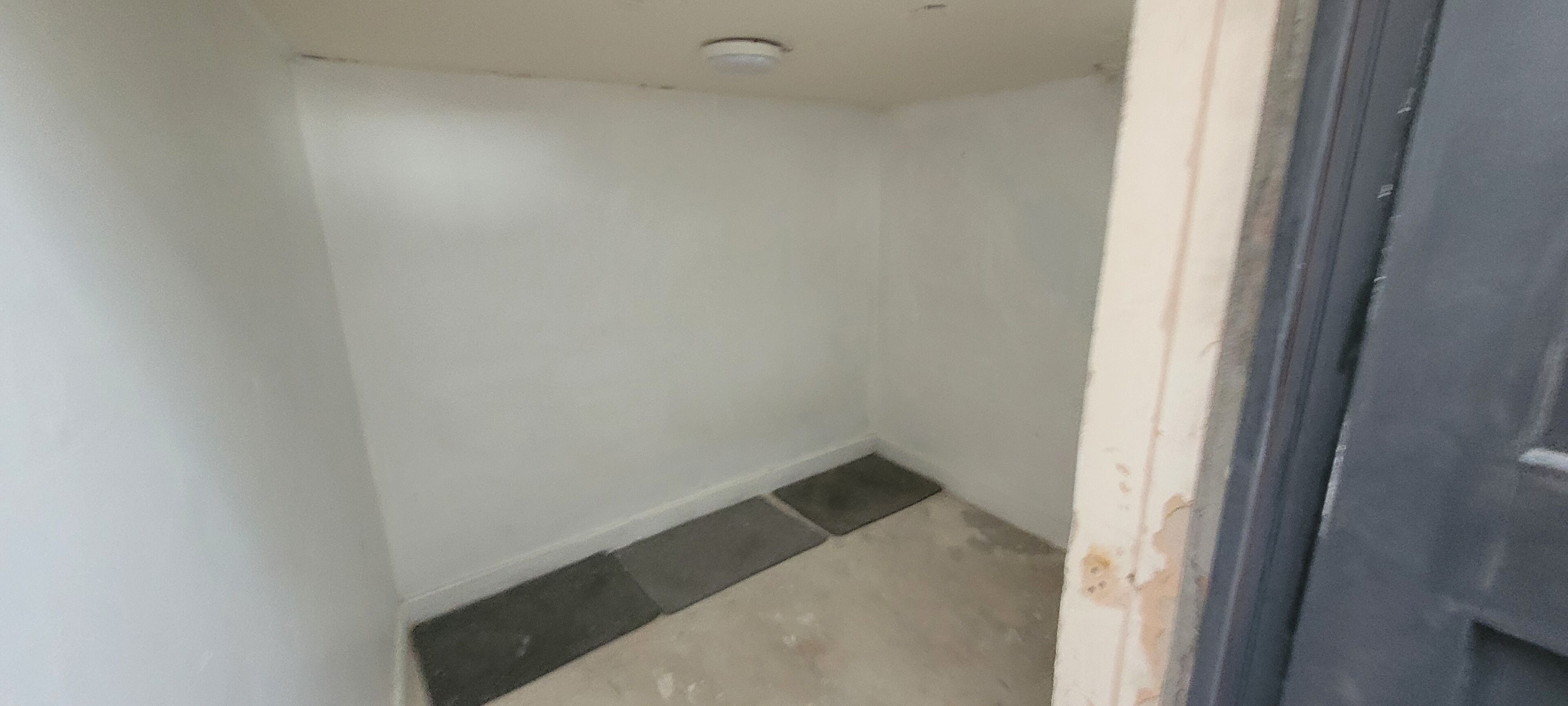 A small, narrow room with white walls and a tiled floor.