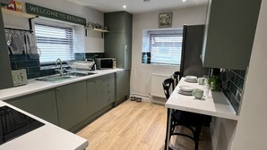 A compact kitchen with a microwave, sink, and a 'Welcome to Bedlinog' sign.
