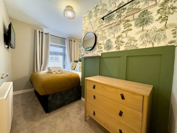 Un dormitorio con cama, cómoda, espejo y ventana con cortinas.