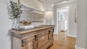 Une console en bois ornée d’un vase rempli de verdure, d’un bol décoratif et d’un livre intitulé « Un endroit simple, le foyer ».