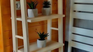 A wooden interior with a white ladder shelf holding folded towels and two potted plants. - Studio Duplex Avec Terrasse Ombragée (Lempdes)