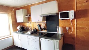 A compact kitchen with white cabinets, a black stove, and a microwave. - Studio Duplex Avec Terrasse Ombragée (Lempdes)