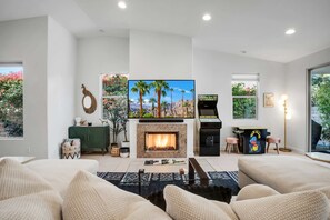 A modern living room with a flat-screen TV, a fireplace, and a gaming console.