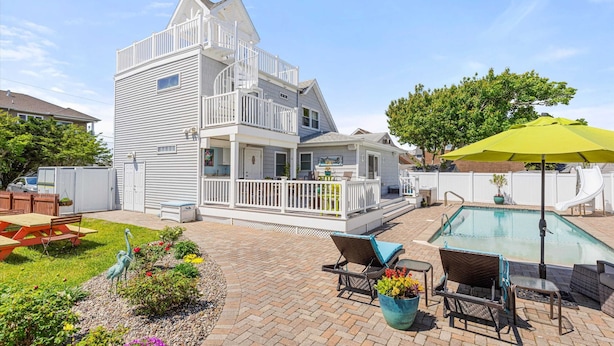 A two-story house with a balcony, a swimming pool, and outdoor seating. - Four Bedroom West OC Home with Pool and Hot Tub (Ocean City)
