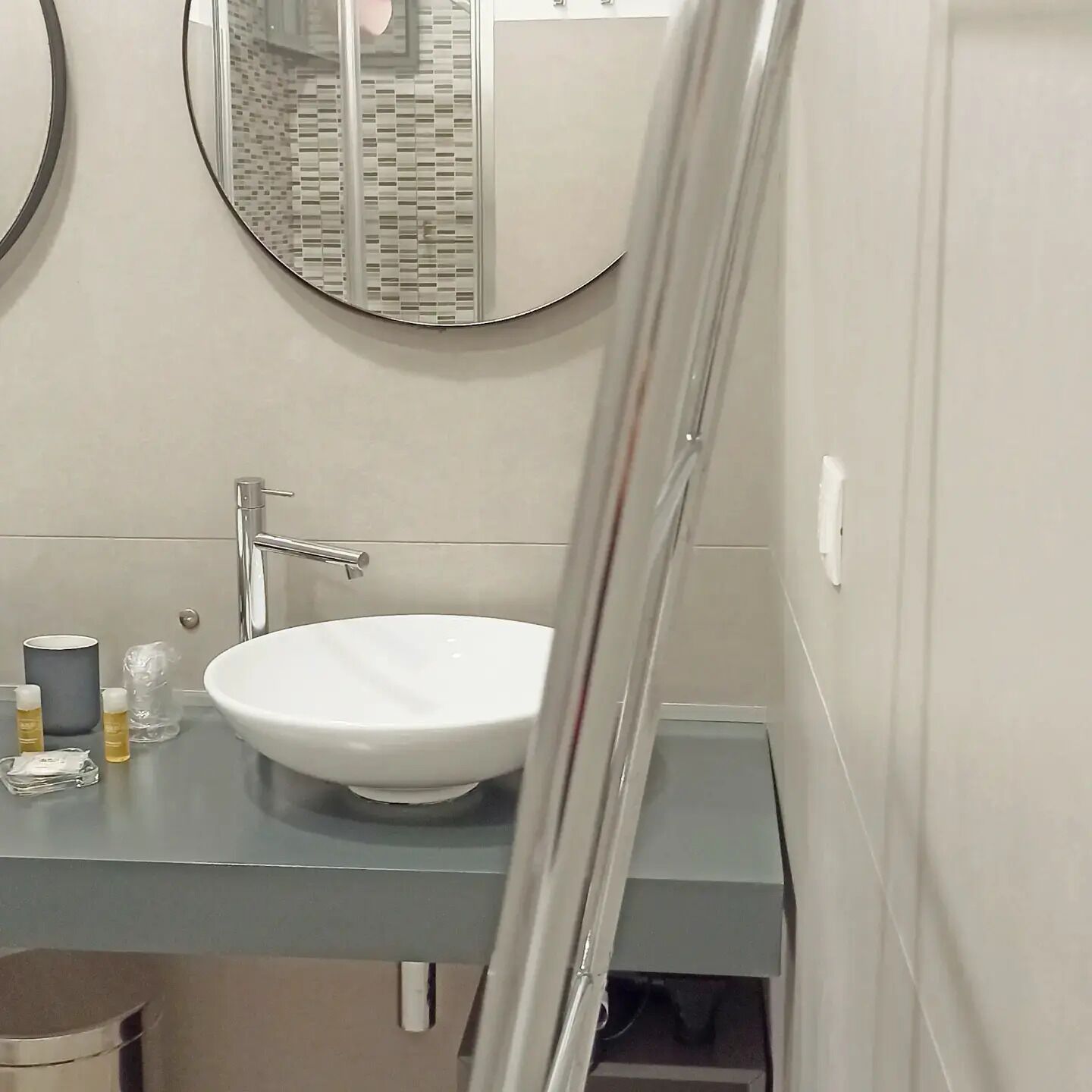 Une salle de bain avec un lavabo blanc, un miroir rond et des toilettes.