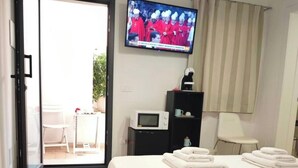 Habitación de hotel con cama, televisión, microondas, una mesita y una silla.