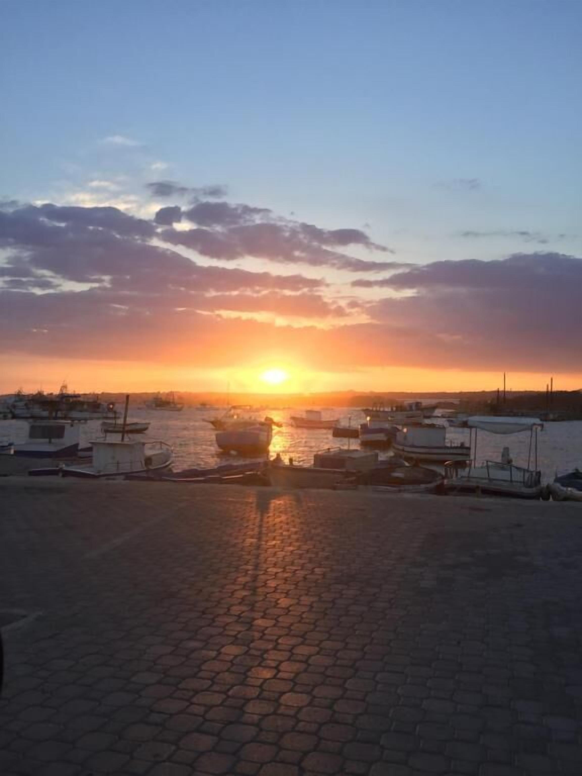 A sunset over a harbor with boats docked.