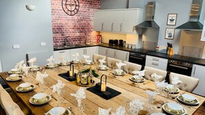 A dining area with a long wooden table set for a meal, surrounded by chairs.