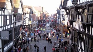 Una animada calle de estilo medieval con estrechos senderos y edificios tradicionales de entramado de madera.