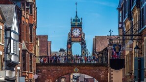 Una torre de reloj histórica con gente en un puente.