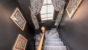 A staircase with a black railing and patterned curtains. - Tudor House - Hot Tubs Chester City Sleeps 30 (Cheshire West and Chester)