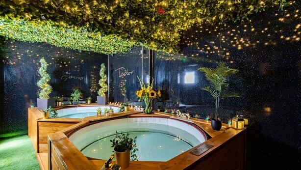 A spa area with a large circular hot tub, surrounded by wooden benches and potted plants. - Tudor House - Hot Tubs Chester City Sleeps 30 (Cheshire West and Chester)