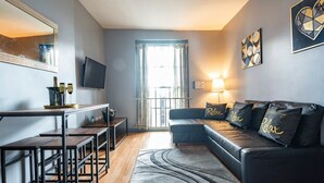 A modern living room with a sofa, a coffee table, a TV, and a dining area with a table and chairs. - The Berwyn 2 bedroomed Apartment | Central Wrexham (Wrexham)