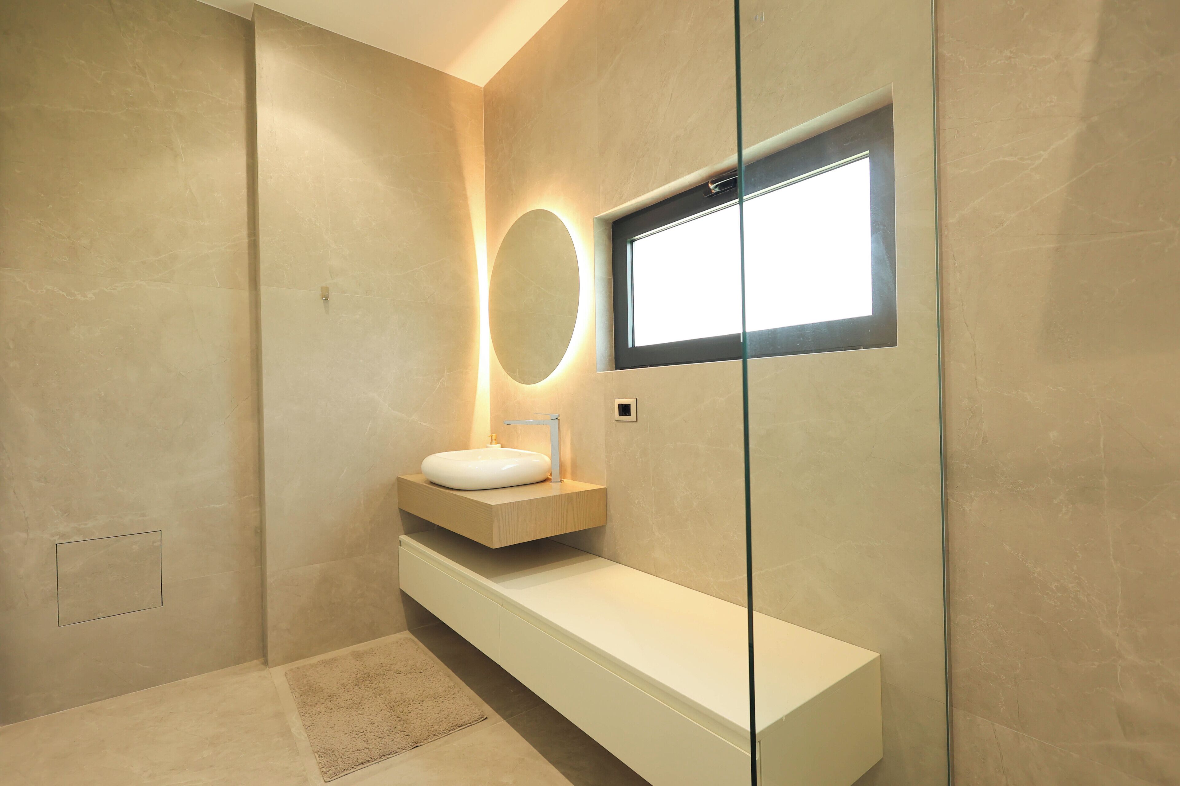 Une salle de bain moderne avec un grand miroir, un miroir rond et un miroir rectangulaire.