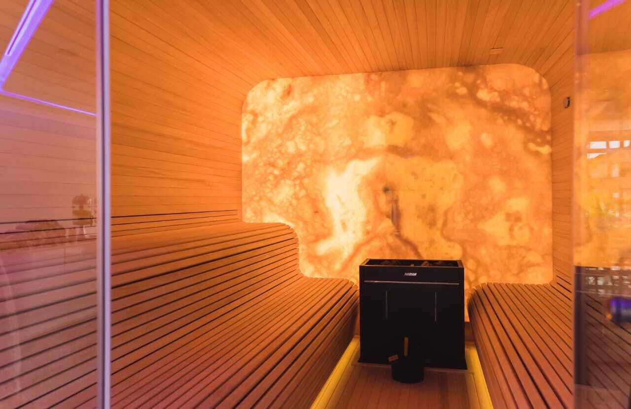 A sauna with wooden benches and a marble wall.